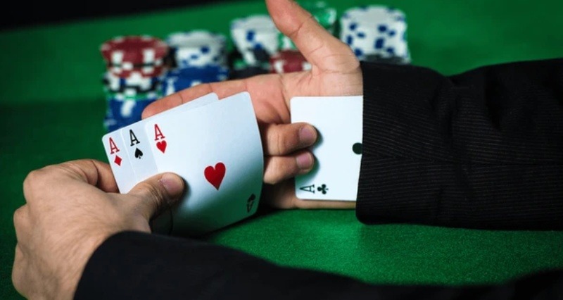 بازیکن پوکر که چند کارت آس پنهان را در دست نگه داشته